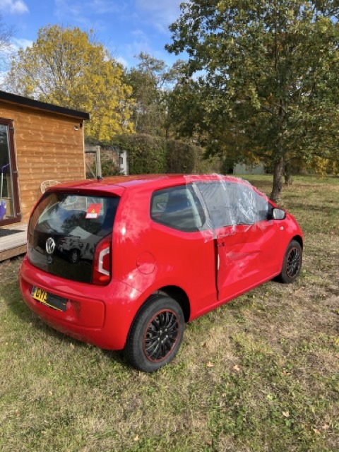 VW Up project car parked beside a wooden shed